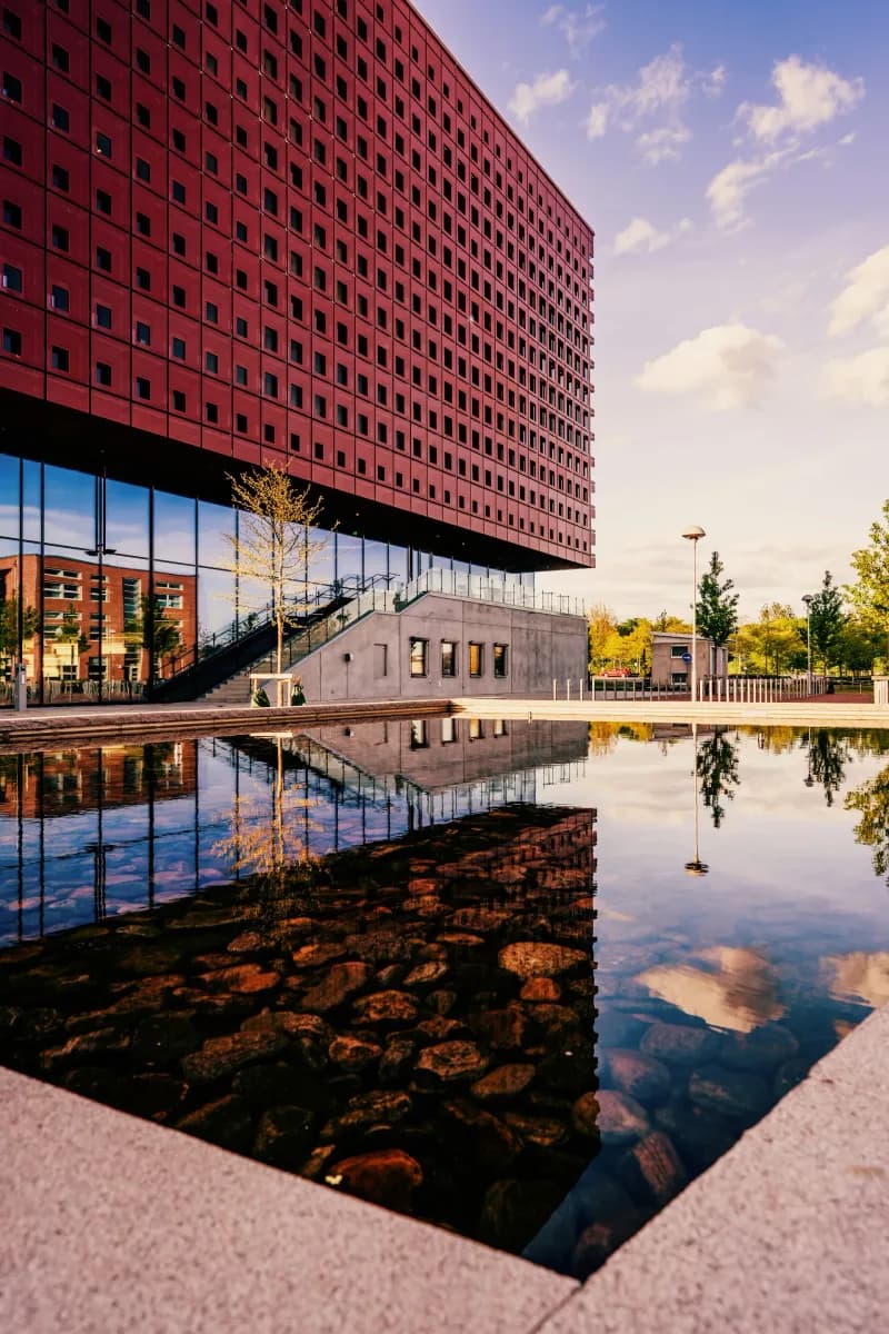 Modern tegelbyggnad vid en reflekterande damm i Linköping